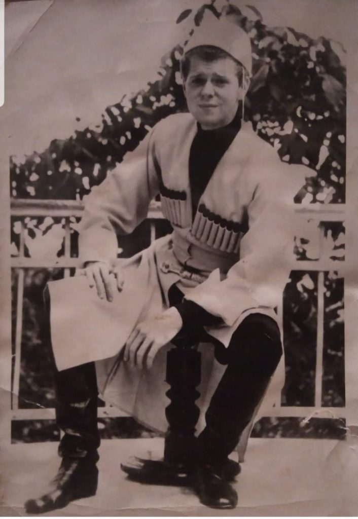 Van Cliburn est assis et porte le tchokha, un costume traditionnel géorgien emblématique. On distingue nettement les masrebi (étuis à cartouches) sur sa poitrine et une coiffe traditionnelle sur sa tête.