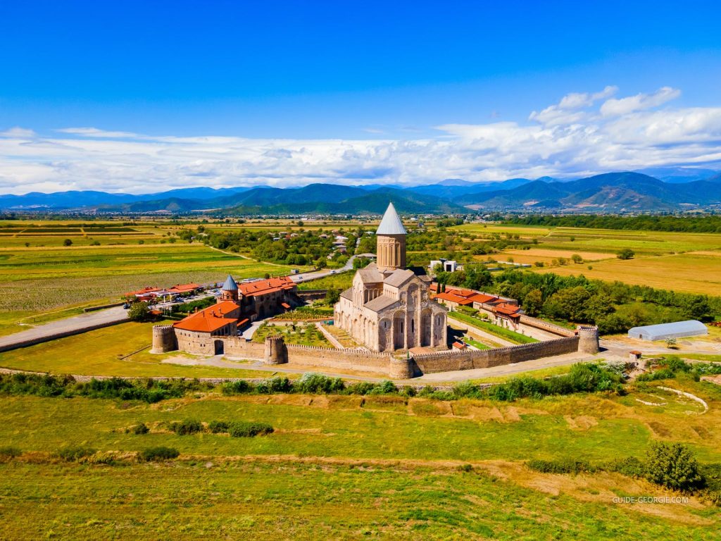 Vue panoramique aérienne d'un complexe monastique orthodoxe en Kakheti, avec église centrale et bâtiments annexes entourés de paysage rural