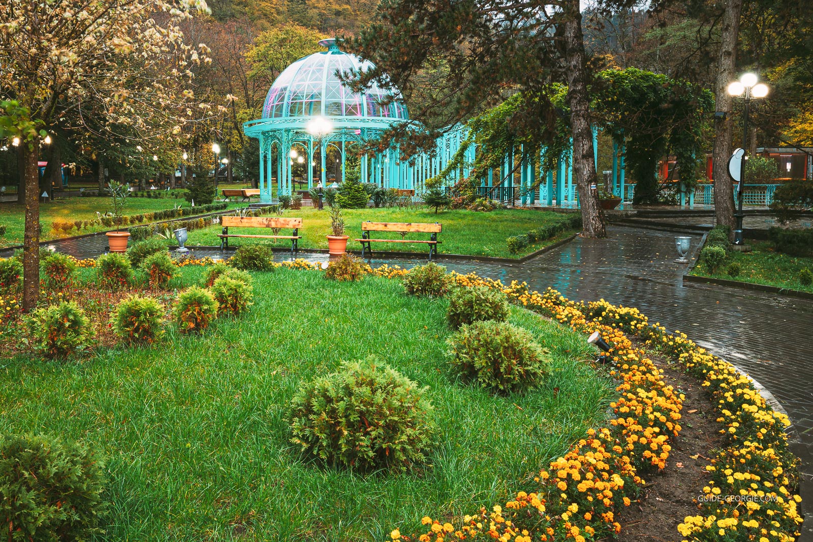 Pavillon dans un parc d'automne entouré d'arbres aux feuilles dorées, éclairé en soirée
