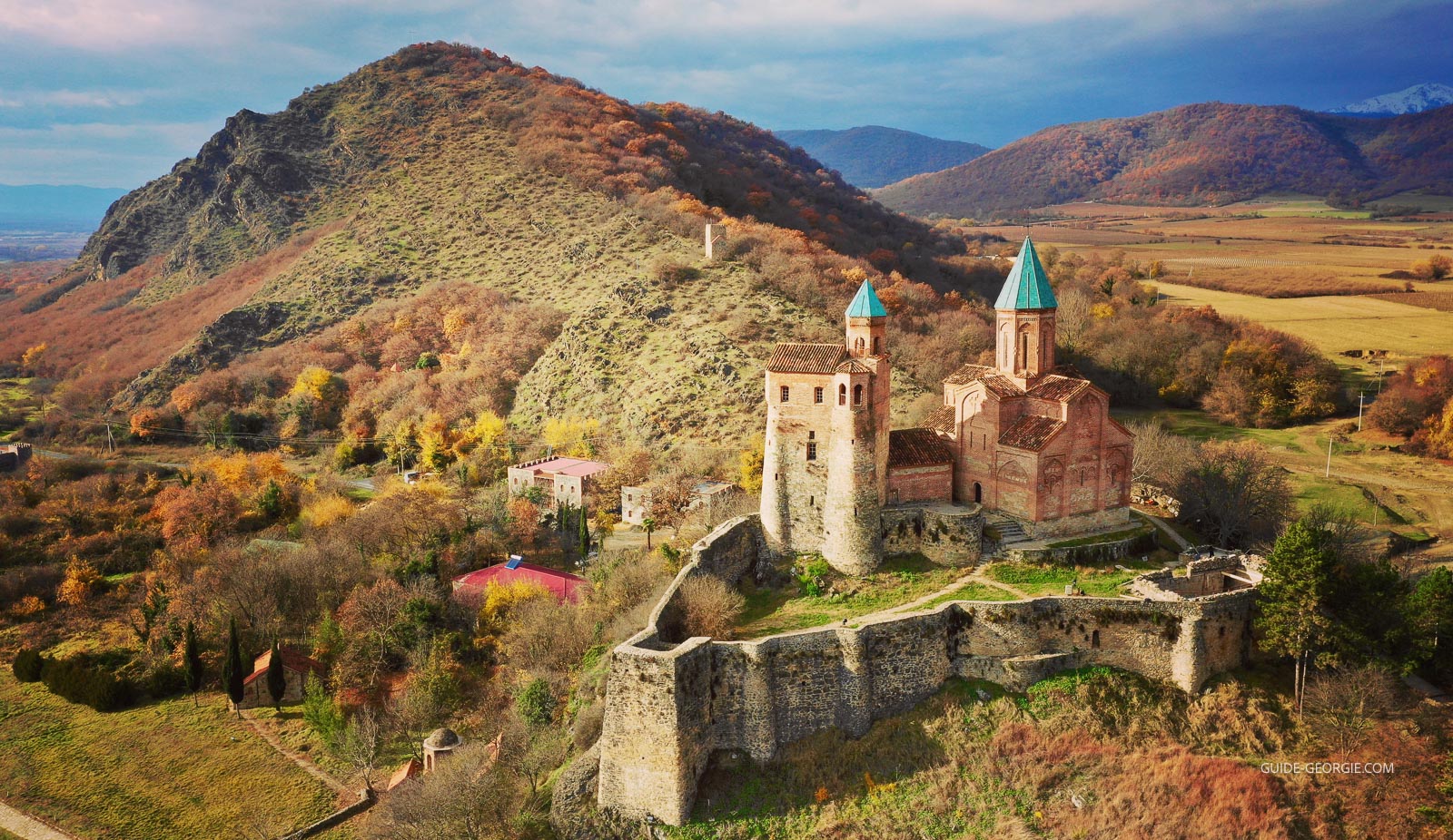 Vue du château fort et de l'église en pierre perchés sur une colline, entourés de végétation