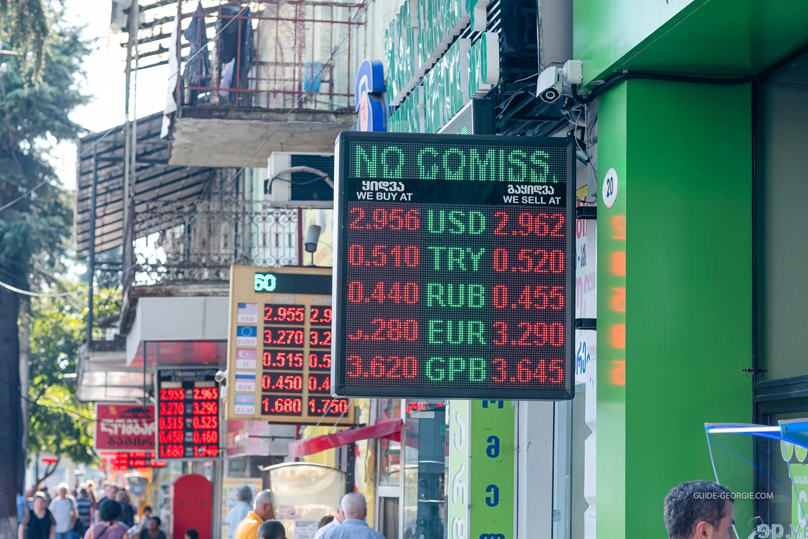 Façades de plusieurs bureaux de change alignés le long d'une rue urbaine avec panneaux de taux de change