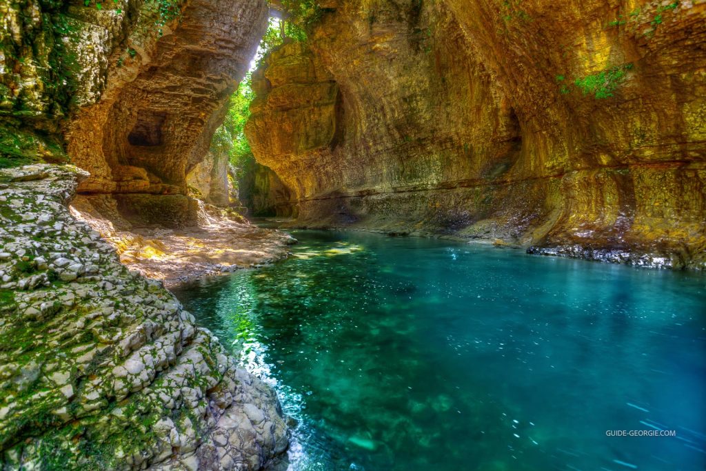 Vue d'un canyon rocheux avec une rivière verte traversant une vallée bordée de falaises et de végétation