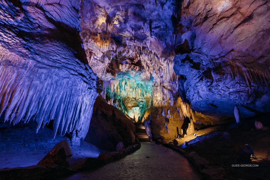 Intérieur d'une grande grotte souterraine avec stalactites et formations calcaires éclairées artificiellement