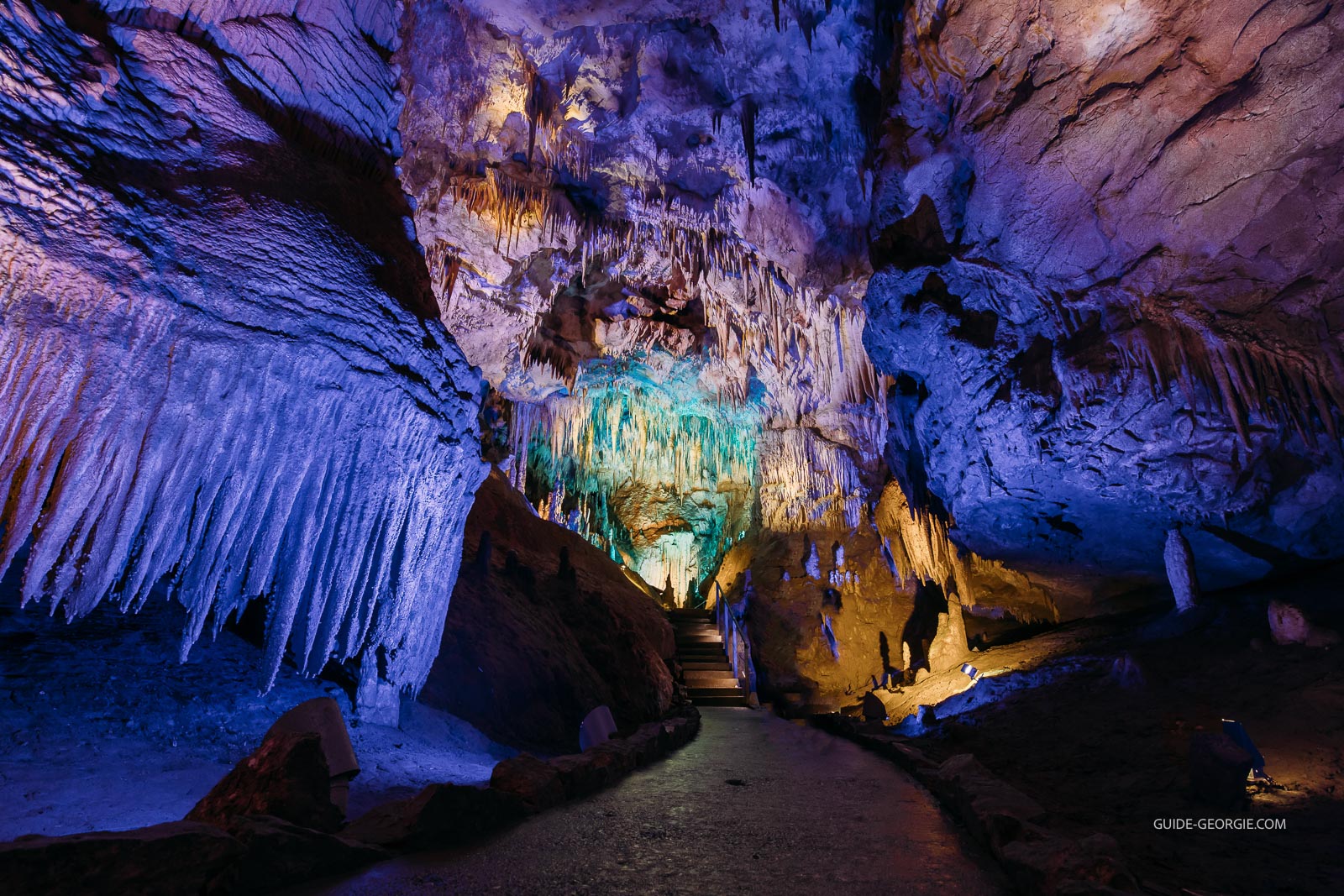 Intérieur d'une grande grotte souterraine avec stalactites et formations calcaires éclairées artificiellement