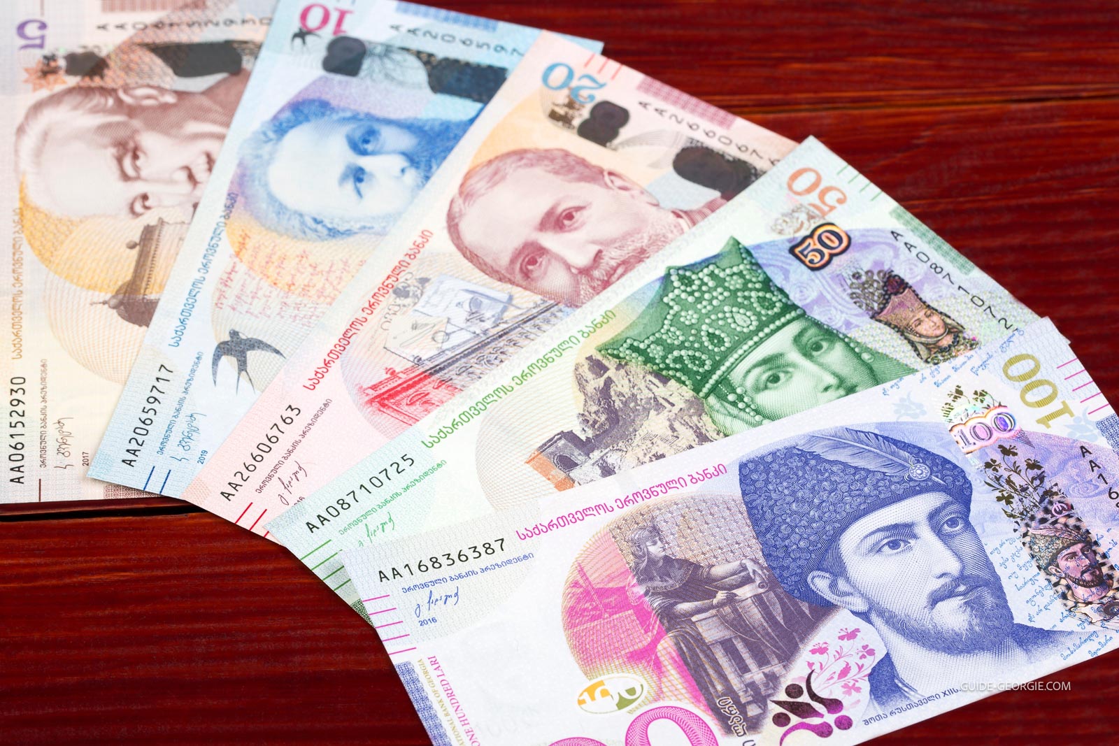 Billets de lari géorgien empilés et éparpillés sur un fond sombre évoquant un contexte d'affaires