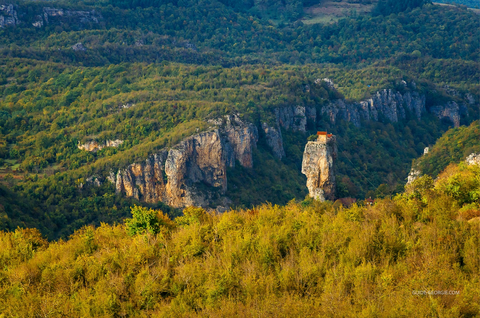Pilier rocheux isolé avec une petite église orthodoxe et une cellule de moine au sommet, sous un ciel nuageux
