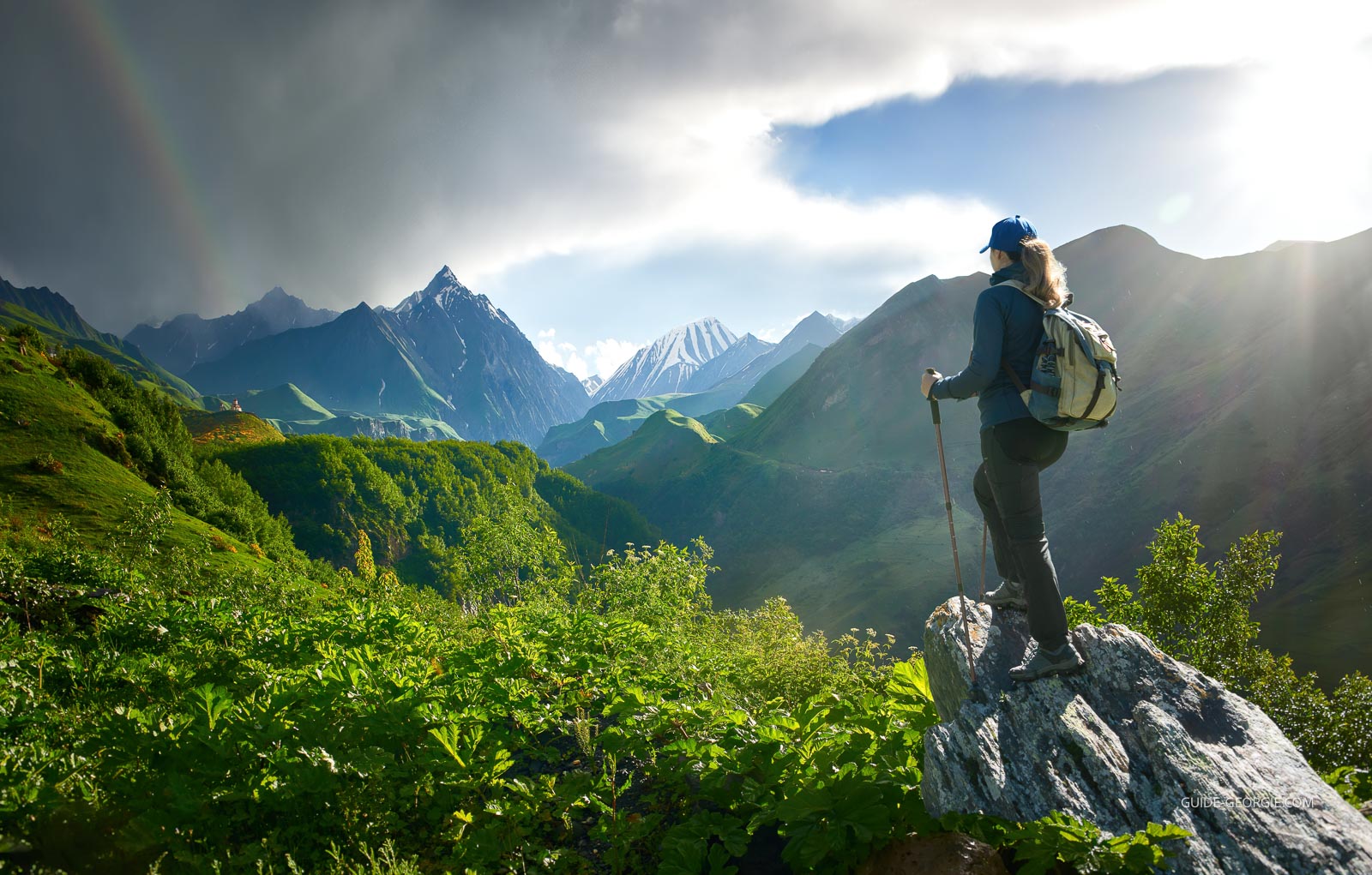 Femme avec sac à dos regardant un paysage de montagnes et de forêt sous des nuages