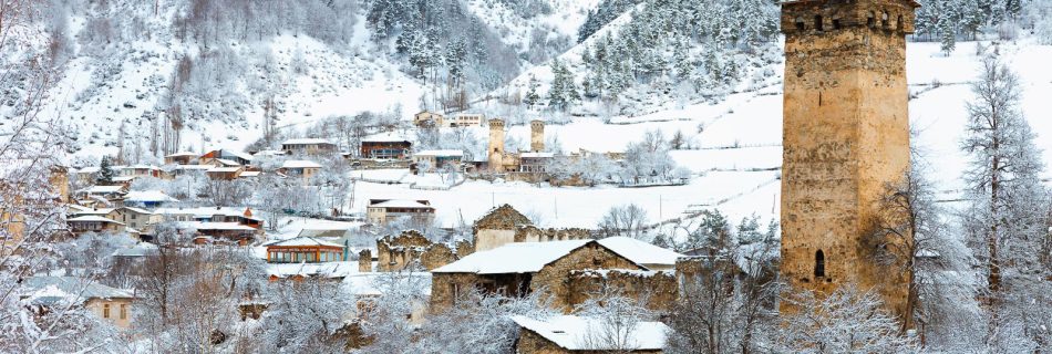 Vue panoramique de tours de pierre médiévales et de maisons dans un paysage montagneux enneigé